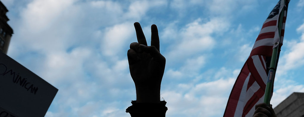 peace sign during muslim travel ban rally with american flag